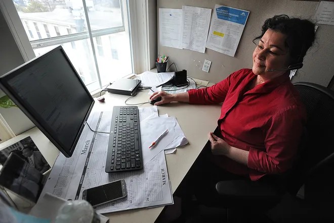 A Mass 211 information and referral specialist is shown speaking with a client in this 2020 file photo.